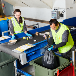 two cleaners sorting materials on a conveyor belt for recycling